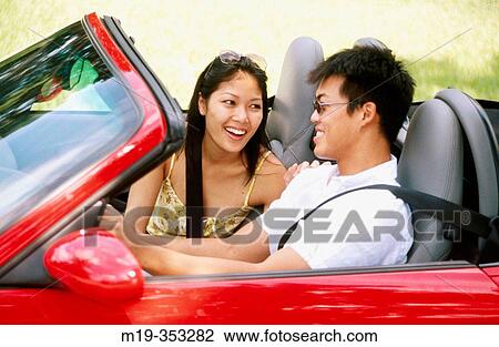 Stock Image - Asain couple in a convertible. Fotosearch