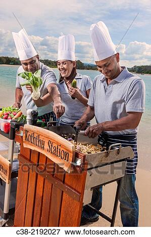 Stock Photo - Asian catering chefs at the beach cooking with a Koththu station. Gold Coast, Queensland, Australia.. Fotosearch