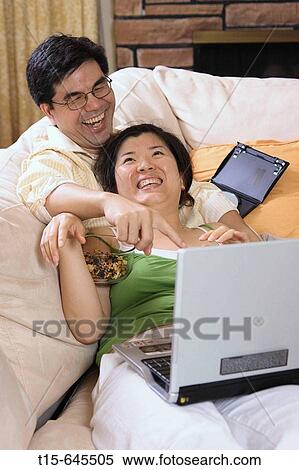 Asian couple in their 30's watching movie on laptop together having fun View Large Photo Image Stock Photography - Asian couple in their 30's watching movie on laptop together having fun. Fotosearch