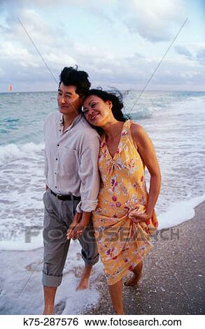Asian couple strolling along the seashore View Large Photo Image Stock Photograph - Asian couple strolling along the seashore. Fotosearch