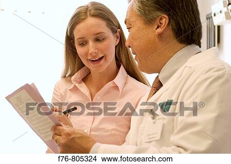 Asian doctor, reviewing patient records with female patient, in exam room of medical office View Large Photo Image Picture - Asian doctor, reviewing patient records with female patient, in exam room of medical office. Fotosearch