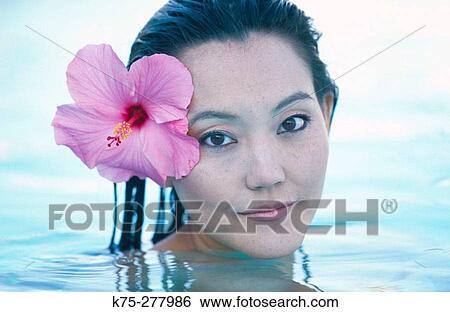 Stock Photograph - Asian girl with hibiscus in her hair. Fotosearch