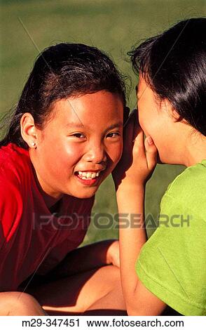 Stock Image - Asian girls wispering. Fotosearch