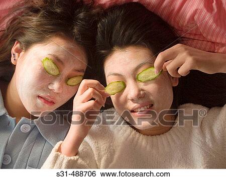 Asian girl(s) with face masks and slices of cucumbers on their eyes as in beauty treatment View Large Photo Image Stock Photograph - Asian girl(s) with face masks and slices of cucumbers on their eyes as in beauty treatment. Fotosearch