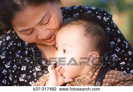 Stock Image - Asian grandmother holding her grandchild. Fotosearch