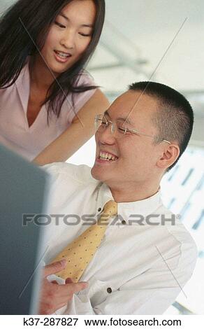 Asian man and woman working at computer in contemporary office View Large Photo Image Stock Photo - Asian man and woman working at computer in contemporary office. Fotosearch
