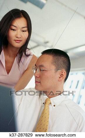 Asian man and woman working at computer in contemporary office View Large Photo Image Stock Photo - Asian man and woman working at computer in contemporary office. Fotosearch