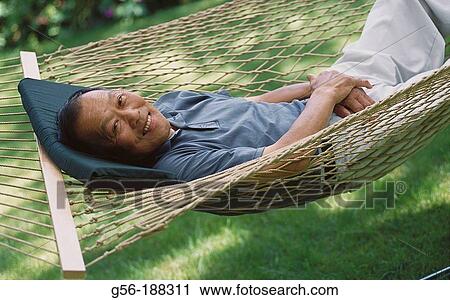 Stock Image - Asian man in hammock, 60 years old. Fotosearch