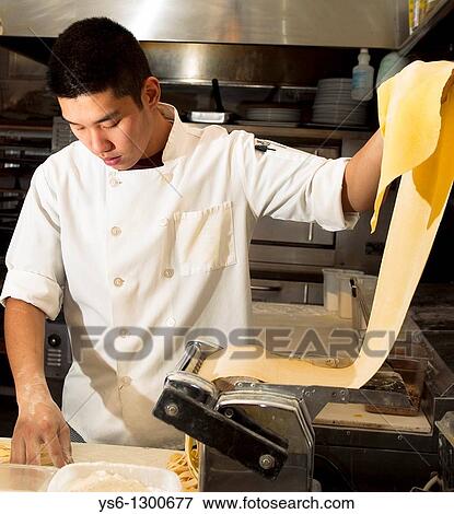 Asian man making pasta in restaurant kitchen wearing chef coat View Large Photo Image Stock Photo - Asian man making pasta in restaurant kitchen wearing chef coat. Fotosearch