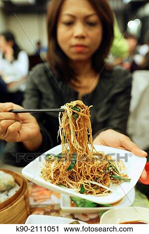 Stock Image - Asian woman eating chinese noodles, Kowloon, Hong Kong, China, East Asia.. Fotosearch