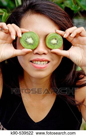Asian woman holding Kiwi slices in front of her eyes View Large Photo Image Stock Image - Asian woman holding Kiwi slices in front of her eyes. Fotosearch