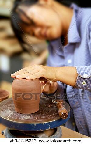 Asian woman moulding clay on a pottery wheel View Large Photo Image Stock Image - Asian woman moulding clay on a pottery wheel. Fotosearch