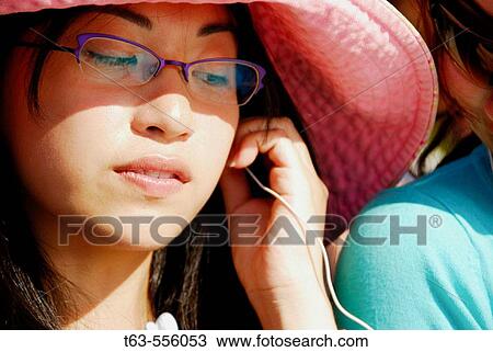 asian woman putting earphone in ear View Large Photo Image Stock Image - asian woman putting earphone in ear. Fotosearch