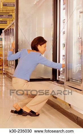 Stock Image - Asian woman shopping at grocery store.. Fotosearch