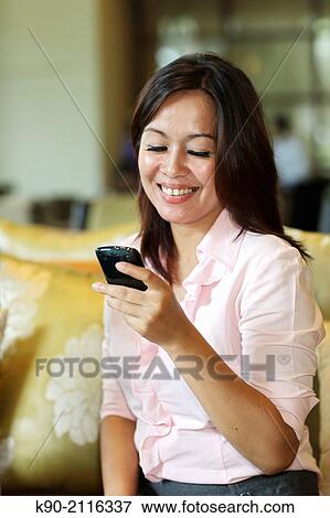 Stock Photo - Asian women holding a smartphone, Jakarta, Indonesia, Southeast Asia.. Fotosearch
