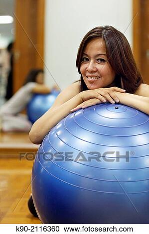 Stock Image - Asian women leaning on a gymnastic ball, Jakarta, Indonesia, Southeast Asia.. Fotosearch