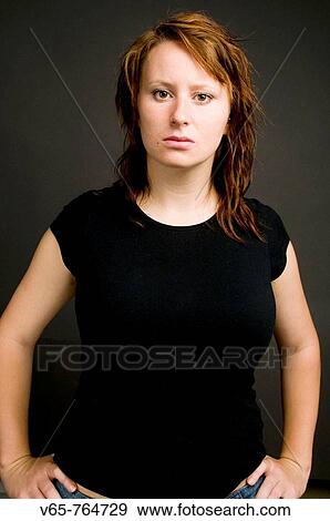Assertive looking defiant red haired young woman standing with her hands on her hips View Large Photo Image Stock Photo - Assertive looking defiant red haired young woman standing with her hands on her hips. Fotosearch