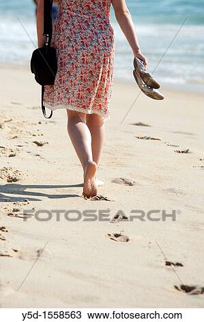 Stock Image - Atlantic Ocean beach, Atlantic Ocean coast, woman walking barefoot on the beach, Portugal. Fotosearch