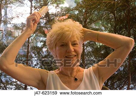 Attractive 70 year old lady, brushing her hair outside. View Large Photo Image Stock Photo - Attractive 70 year old lady, brushing her hair outside.. Fotosearch