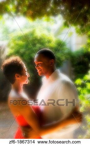 Attractive and romantic African American black couple snuggling in sunshine outdoors all dressed up beautifully View Large Photo Image Picture - Attractive and romantic African American black couple snuggling in sunshine outdoors all dressed up beautifully. Fotosearch
