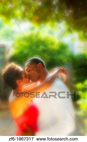 Attractive and romantic African American black couple snuggling in sunshine outdoors all dressed up beautifully View Large Photo Image Stock Photo - Attractive and romantic African American black couple snuggling in sunshine outdoors all dressed up beautifully. Fotosearch