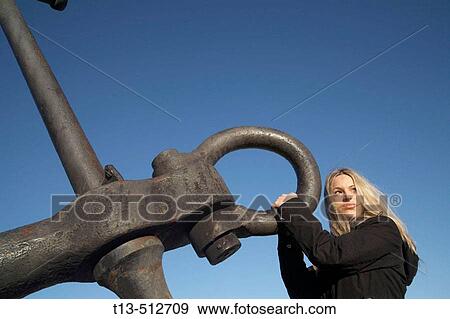 Attractive blond girl holding ship's anchor isolated against blue sky View Large Photo Image Stock Photo - Attractive blond girl holding ship's anchor isolated against blue sky. Fotosearch