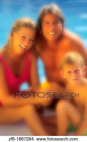Picture - Attractive family relaxing by the pool putting on suntan lotion. Fotosearch