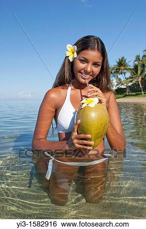 Stock Photograph - Attractive girl with plumeria flower and coconut drink in Lahaina, Maui, Hawaii. Fotosearch