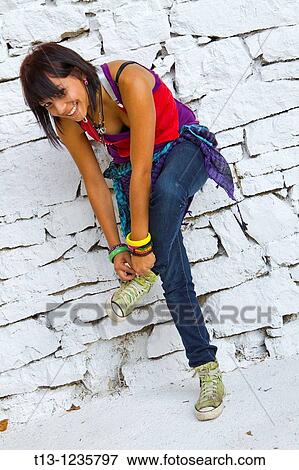 Stock Photo - Attractive teen girl is tying sneaker laces. Fotosearch