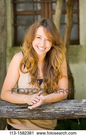 Attractive very happy young woman is leaning on a wooden fence View Large Photo Image Stock Image - Attractive very happy young woman is leaning on a wooden fence. Fotosearch