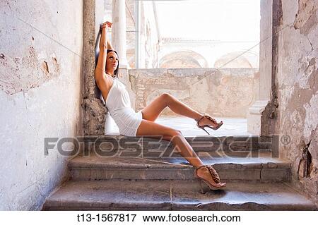 Attractive woman is sitting wide in a short White Summer dress and high-heeled shoes View Large Photo Image Stock Photo - Attractive woman is sitting wide in a short White Summer dress and high-heeled shoes. Fotosearch