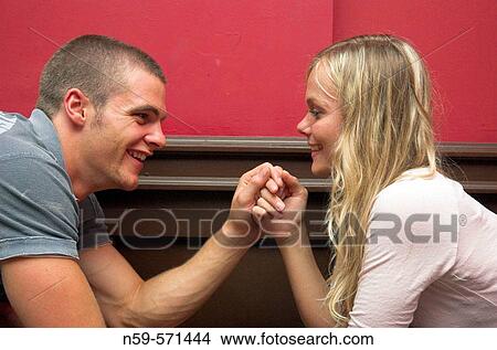 Attractive young couple flirting across a table in a bar. View Large Photo Image Picture - Attractive young couple flirting across a table in a bar.. Fotosearch