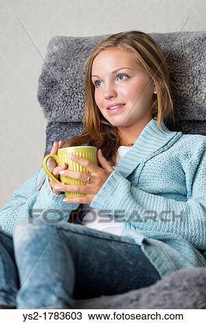 Stock Image - Attractive young female at home holding a mug with coffee or tea. Fotosearch