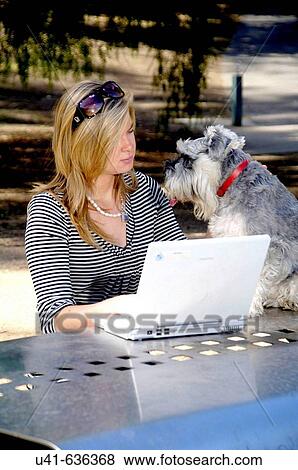 Attractive young female working on her computer in the gardens with the help of her dog View Large Photo Image Stock Photo - Attractive young female working on her computer in the gardens with the help of her dog. Fotosearch