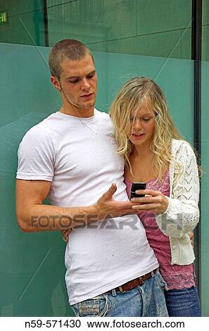 Attractive young urban couple, looking at messages on mobile phone. View Large Photo Image Stock Image - Attractive young urban couple, looking at messages on mobile phone.. Fotosearch