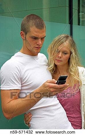 Attractive young urban couple, looking at messages on mobile phone. View Large Photo Image Stock Image - Attractive young urban couple, looking at messages on mobile phone.. Fotosearch