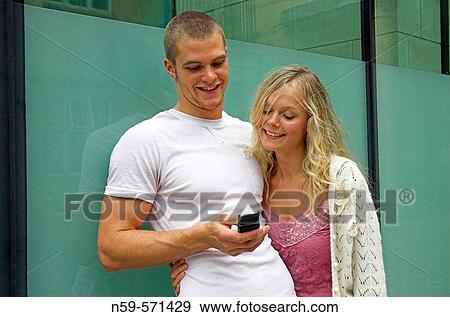 Attractive young urban couple, looking at messages on mobile phone. View Large Photo Image Stock Photo - Attractive young urban couple, looking at messages on mobile phone.. Fotosearch