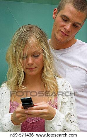 Attractive young urban couple, looking at messages on mobile phone. View Large Photo Image Stock Photograph - Attractive young urban couple, looking at messages on mobile phone.. Fotosearch