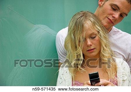 Attractive young urban couple, looking at messages on mobile phone. View Large Photo Image Stock Photography - Attractive young urban couple, looking at messages on mobile phone.. Fotosearch