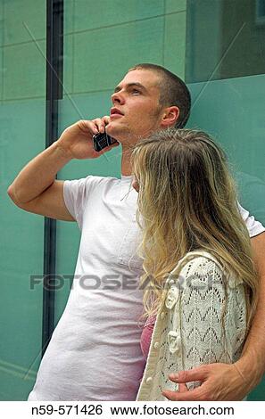 Attractive young urban couple, man talking on mobile phone View Large Photo Image Stock Photograph - Attractive young urban couple, man talking on mobile phone. Fotosearch