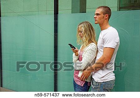 Attractive young urban couple, she is looking at messages on mobile phone. View Large Photo Image Stock Photo - Attractive young urban couple, she is looking at messages on mobile phone.. Fotosearch