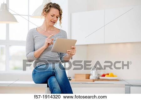 Attractive young woman communicating on her tablet computer at home View Large Photo Image Stock Image - Attractive young woman communicating on her tablet computer at home. Fotosearch