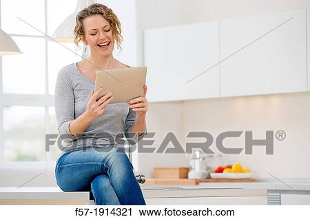 Attractive young woman communicating on her tablet computer at home View Large Photo Image Stock Image - Attractive young woman communicating on her tablet computer at home. Fotosearch