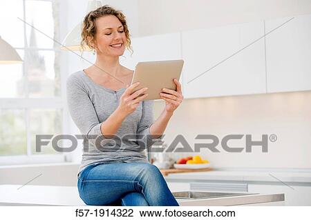 Attractive young woman communicating on her tablet computer at home View Large Photo Image Stock Image - Attractive young woman communicating on her tablet computer at home. Fotosearch