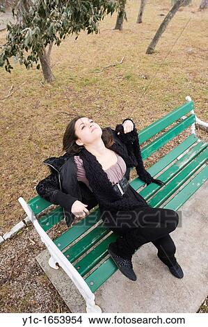 Picture - Attractive young woman daydreaming in park. Fotosearch