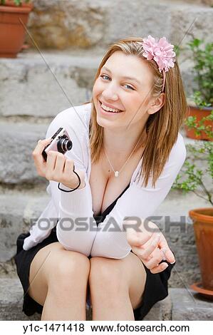 Stock Photo - Attractive young woman happy and smiling with a photo camera in hand. Fotosearch