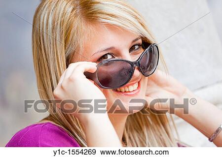 Attractive young woman happy and smiling looking over sunglasses View Large Photo Image Stock Photo - Attractive young woman happy and smiling looking over sunglasses. Fotosearch