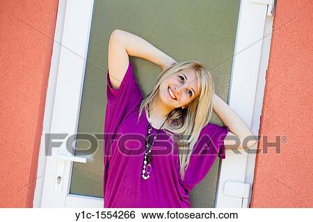 Stock Photograph - Attractive young woman happy and smiling posing sideways. Fotosearch