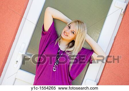 Stock Photography - Attractive young woman happy and smiling posing sideways. Fotosearch