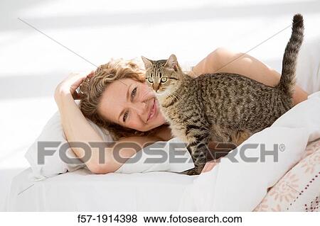 Attractive young woman in bed with her cat View Large Photo Image Stock Photo - Attractive young woman in bed with her cat. Fotosearch